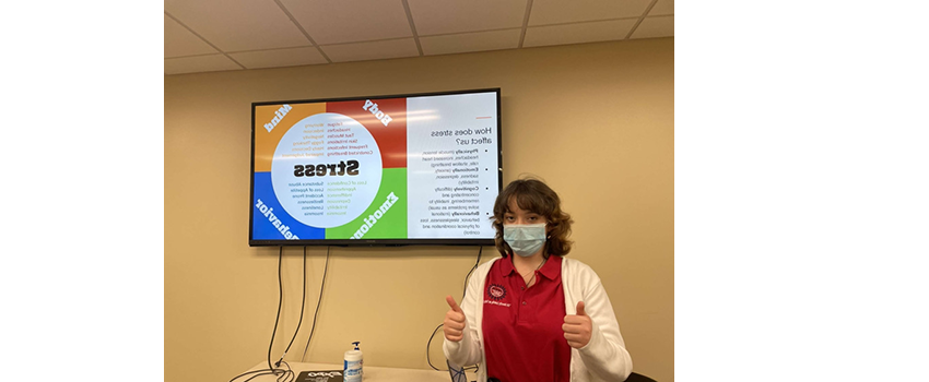 Student in front of screen with a presentation in the background about stress.